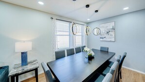 A dining area with a long table, chairs, a vase with flowers, and a lamp. - Tremendous space with covered patio in central McKinney (McKinney)