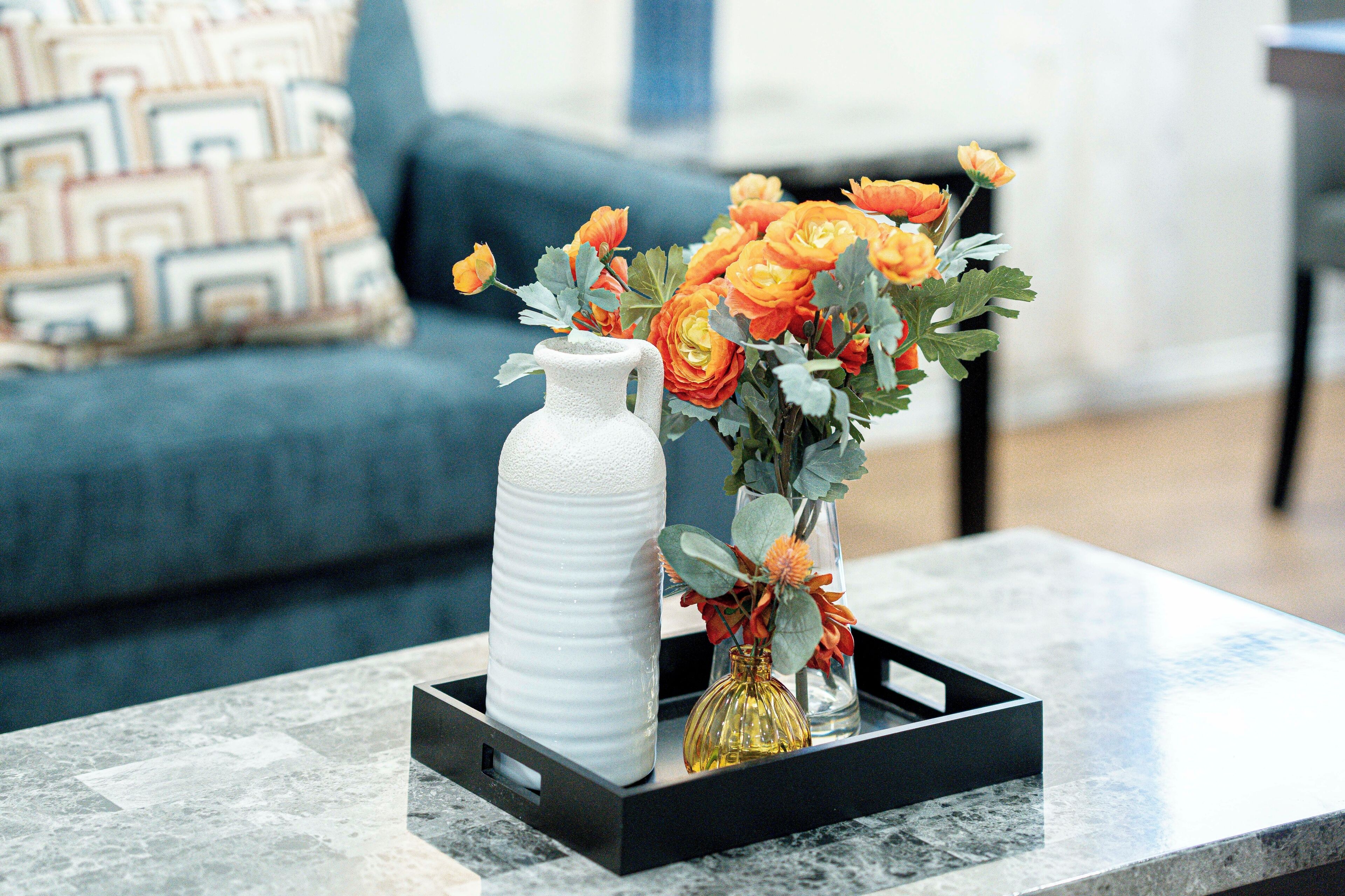 Une table basse en marbre sur laquelle sont posés trois vases remplis de fleurs.