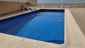 A rectangular swimming pool with a tiled edge, surrounded by a white balustrade.