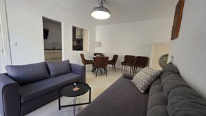 A modern living room with a sofa, a coffee table, and a dining area with chairs.