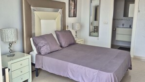 A bedroom with a bed, nightstands, a ceiling fan, a mirror, and a bathroom door.