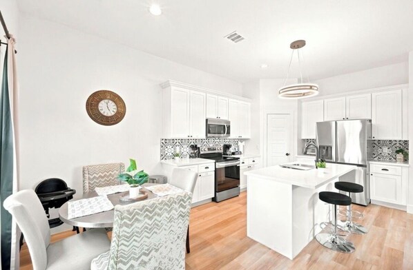 A modern kitchen with white cabinetry, a central island, and bar stools.