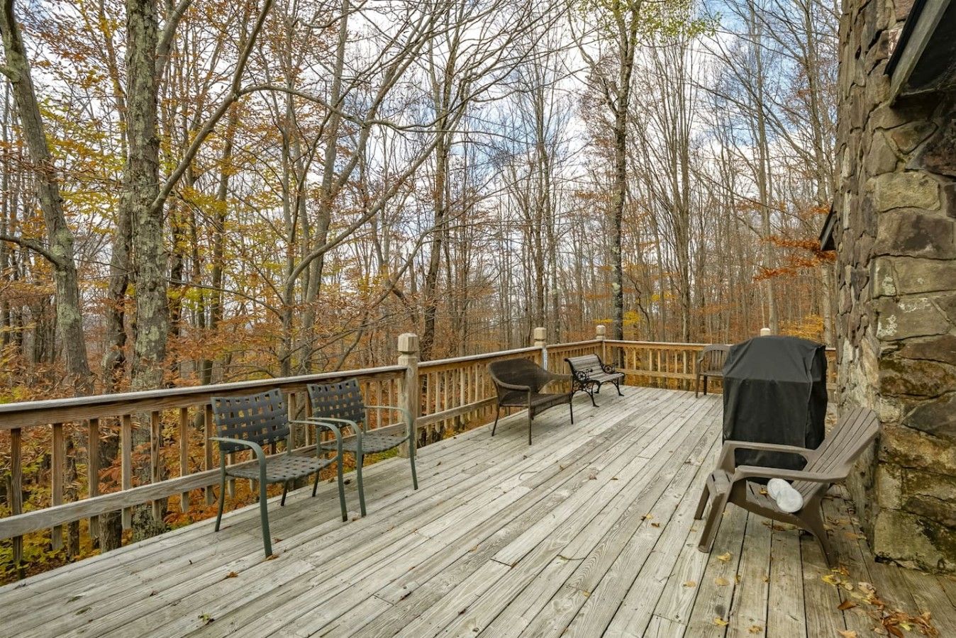 A wooden deck with outdoor seating and a barbecue grill.