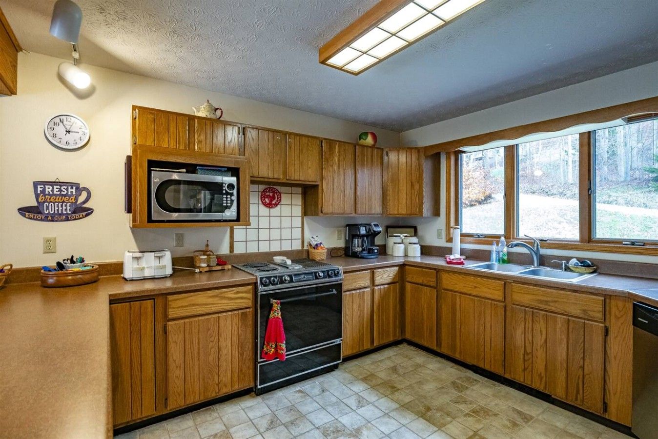 A kitchen with wooden cabinets, a microwave, a stove, and a sink.