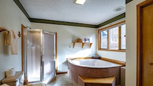 A bathroom with a walk-in shower, a freestanding bathtub, a toilet, and a window providing natural light.
