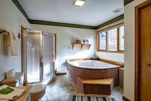 A bathroom with a walk-in shower, a freestanding bathtub, a toilet, and a window providing natural light.