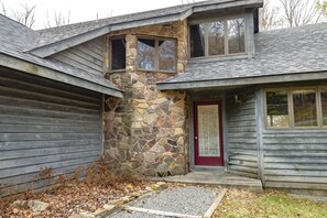 A two-story house with a stone facade and a red door.