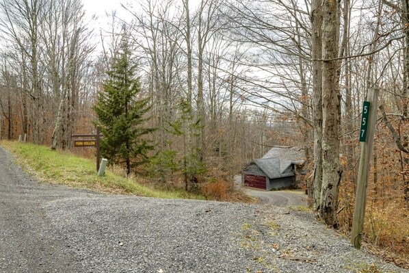 A gravel road leading to a rural area with a small building and a signpost indicating 'Fern Hollow'.
