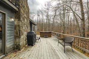 Una terraza de madera con un muro de piedra, mobiliario exterior y un jacuzzi.