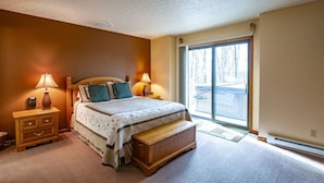 A bedroom with a bed, bedside tables, a bench, and a large window.