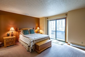 A bedroom with a bed, bedside tables, a bench, and a large window.