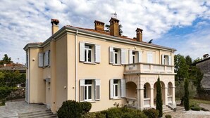 A two-story building with a balcony, a stone pathway, and a small garden.