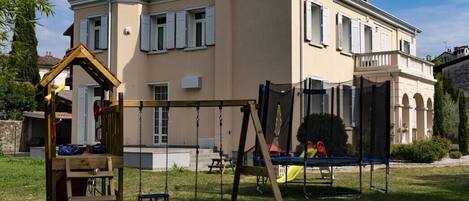 A two-story house with a swing set in the backyard.