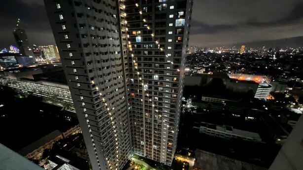 Un edificio de gran altura con varios pisos, ventanas iluminadas y un estacionamiento inferior.