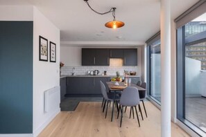 Een moderne keuken met een eethoek, grote ramen en een hanglamp.
