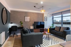 Een moderne woonkamer met een bank, een salontafel, een televisie en een groot raam.