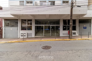 A building with a covered entrance, multiple windows, and a visible staircase leading to an upper floor. - Modern Apartments 900 m From Beira-mar Norte - EOX (Florianópolis)