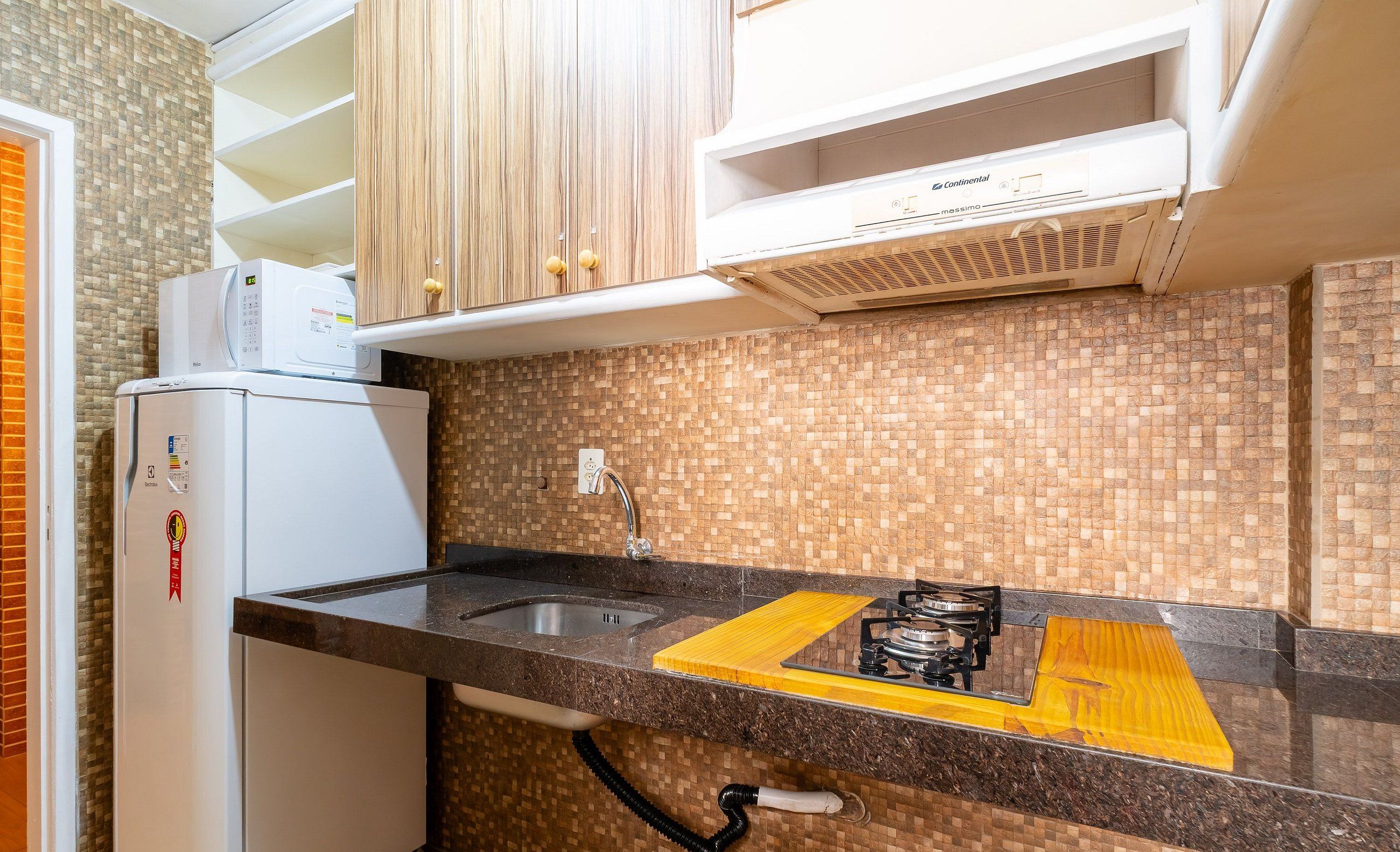 Uma cozinha compacta com micro-ondas embutido, pia e fogão a gás.