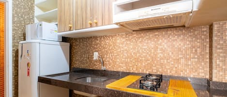 A compact kitchen with a built-in microwave, a sink, and a gas stove.