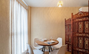 A room with a round wooden table, white chairs, and a decorative wooden partition.