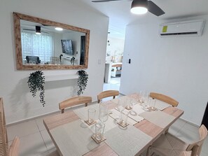 A dining area with a wooden table set for six, surrounded by chairs. A large mirror hangs above the table, reflecting the room. - Design and relaxation in the best area of Cancun. (Cancún)
