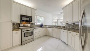 Una cocina moderna con armarios blancos, electrodomésticos de acero inoxidable y una encimera de granito.