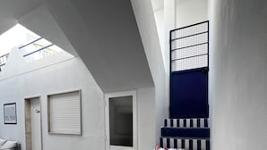 A modern interior with a staircase, a door, and a window with a metal grid.