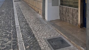 A cobblestone street with buildings on one side.