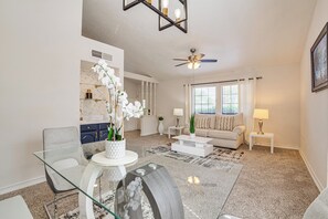 A modern living room with a glass dining table, a sofa, a coffee table, and a ceiling fan. - Fenced-In Yard: Home < 1 Mi to Lake Ray Hubbard! (Garland)
