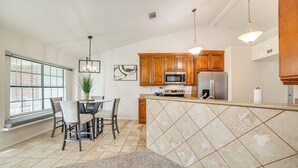 Una cocina moderna con armarios de madera, una isla central y un comedor con sillas y una mesa.