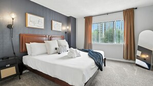 Ein modernes Hotelzimmer mit einem großen Bett, einem Nachttisch, einer Nachttischlampe und einem Fenster mit Vorhängen.