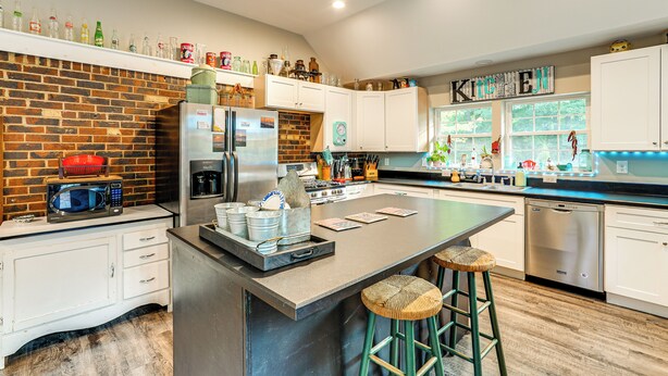 Una cocina moderna con una pared de ladrillo decorativa, electrodomésticos de acero inoxidable y una isla grande con taburetes.