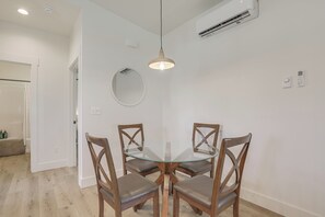 A dining area with a glass table and four wooden chairs, an air conditioning unit, and a round mirror on the wall. - Mtn-Views, Pet-Friendly! Family Home in Ranchester (Ranchester)