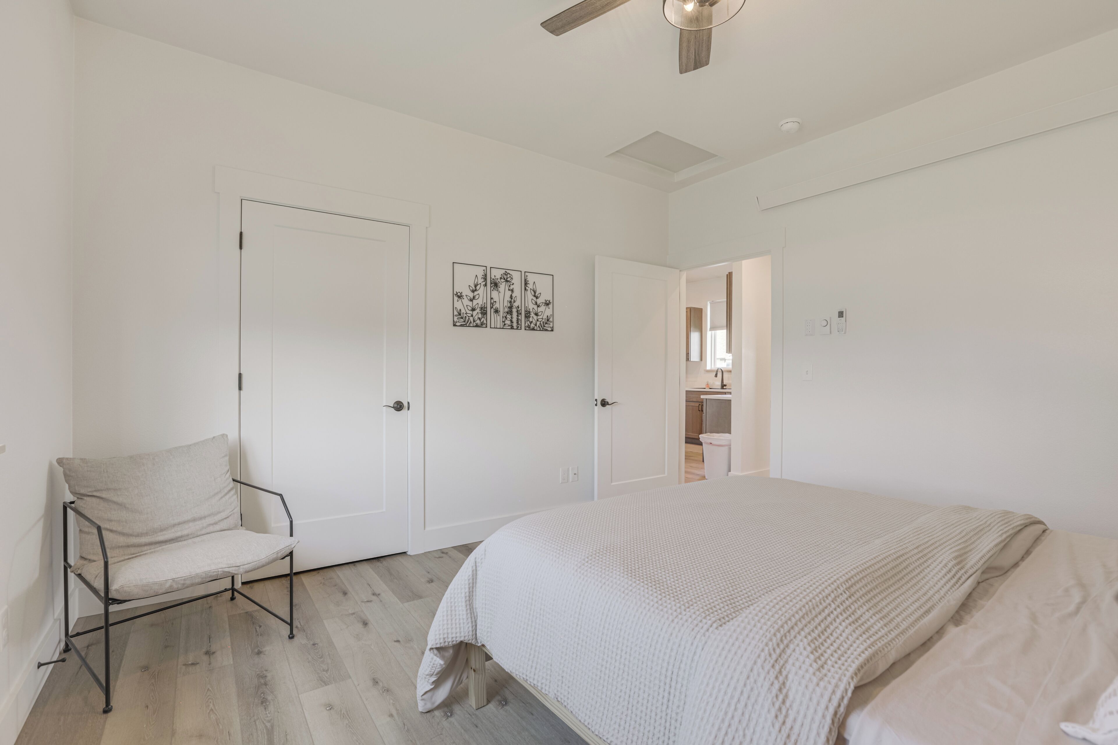 Un dormitorio con cama, una silla, una puerta y un ventilador de techo.