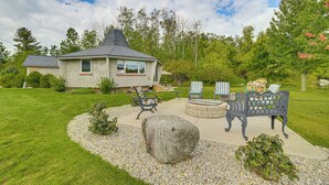 A house with a stone fireplace, outdoor seating, and a well-maintained lawn. - Lakefront Home: Private Dock, Fire Pit, & Kayaks (Charlevoix)