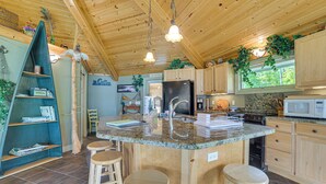 A kitchen with wooden cabinets, a granite countertop, a stainless steel sink, and a built-in microwave. There are three wooden stools and a ladder leaning against the wall. - Lakefront Home: Private Dock, Fire Pit, & Kayaks (Charlevoix)