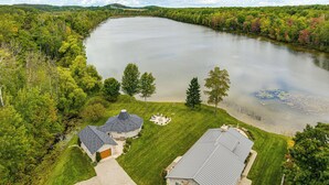 A lakeside property with a house, a lawn, and a dock. - Lakefront Home: Private Dock, Fire Pit, & Kayaks (Charlevoix)