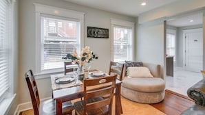 A dining area with a wooden table set for four, surrounded by chairs, a vase with flowers, and a painting on the wall. - Convenient OKC Apartment: 4 Mi to Dtwn! (Oklahoma City)