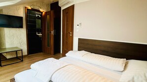 Una habitación de hotel con una cama grande, una mesita, un televisor y un armario.