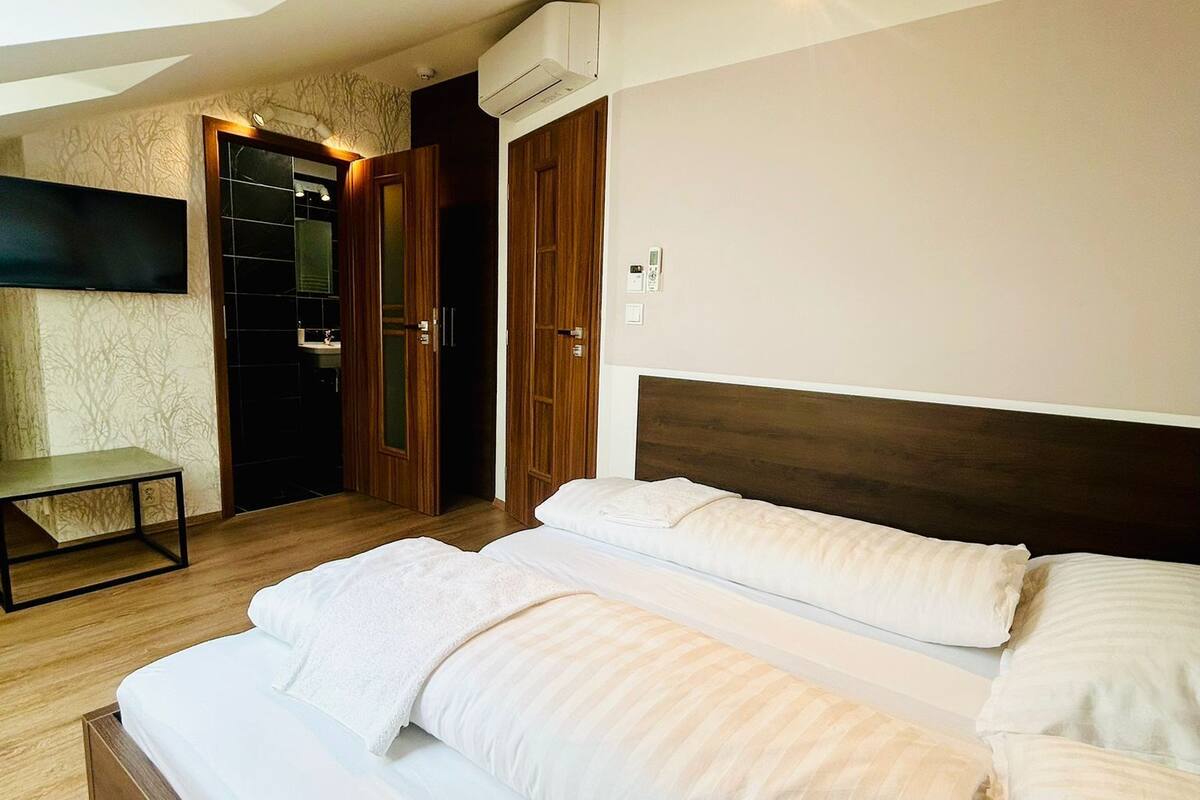 A hotel room with a large bed, a small table, a TV, and a wardrobe.