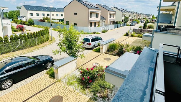 Un barrio residencial con casas modernas, un camino de entrada pavimentado y automóviles estacionados.