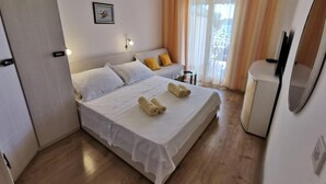 A hotel room with a bed, a small table, a chair, a TV, and a window with curtains. - Apartments Jaman Dalmatica Čiovo (Okrug)