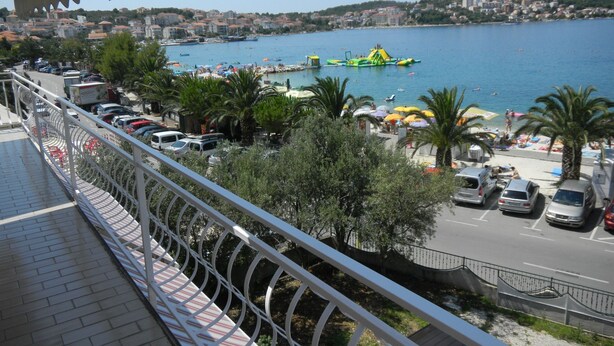 A seaside view from a balcony overlooking a beach with parked cars and a clear blue sea. - Apartments Jaman Dalmatica Čiovo (Okrug)