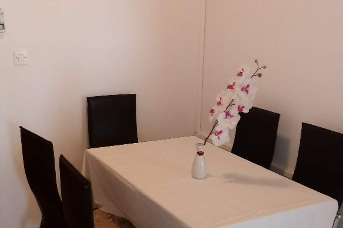 Ein Essbereich mit einem Tisch, der mit einer weißen Tischdecke bedeckt ist, umgeben von schwarzen Stühlen.
