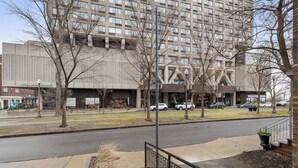 A modern hotel with a large building facade, a parking lot, and a sidewalk with a metal railing. - Perfect Location! Perfect Stay in Québec City! Suite Belle (Québec)