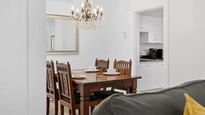 A dining area with a wooden table and chairs, a chandelier, and a kitchen visible through an open door. - Perfect Location! Perfect Stay in Québec City! Suite Belle (Québec)
