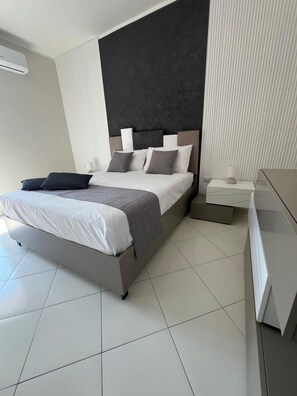 Una camera da letto moderna con un letto, comodini e un tavolino da notte.