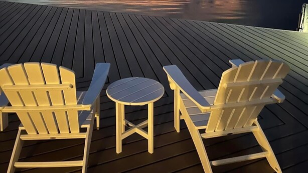 A wooden deck with Adirondack chairs and a small table, overlooking a calm body of water during sunset. - Charming Florida Keys townhome with boat slip in Tavernier 3 bedrooms available (Tavernier)