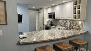 A modern kitchen with a marble countertop, white cabinets, and a built-in wine rack. - Charming Florida Keys townhome with boat slip in Tavernier 3 bedrooms available (Tavernier)
