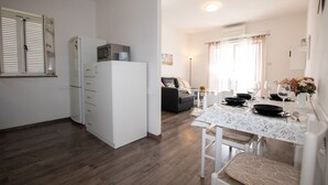 A compact kitchen with a refrigerator, microwave, and dining area with a table and chairs. - Apartments Mirjana IKA (Ika)